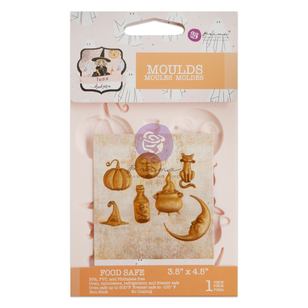 A packaged silicone craft mould is displayed against a white background. The packaging is pastel peach and cream with the word “MOULDS” prominently printed near the top, along with branding for Prima Marketing and the “Luna” collection. In the center is a preview image showing whimsical Halloween-inspired cast pieces in an antique gold finish. The designs include a pumpkin, a round moon face with expressive eyes and lips, a seated cat with a curled tail, a crooked witch’s hat, a bubbling cauldron, a potion 