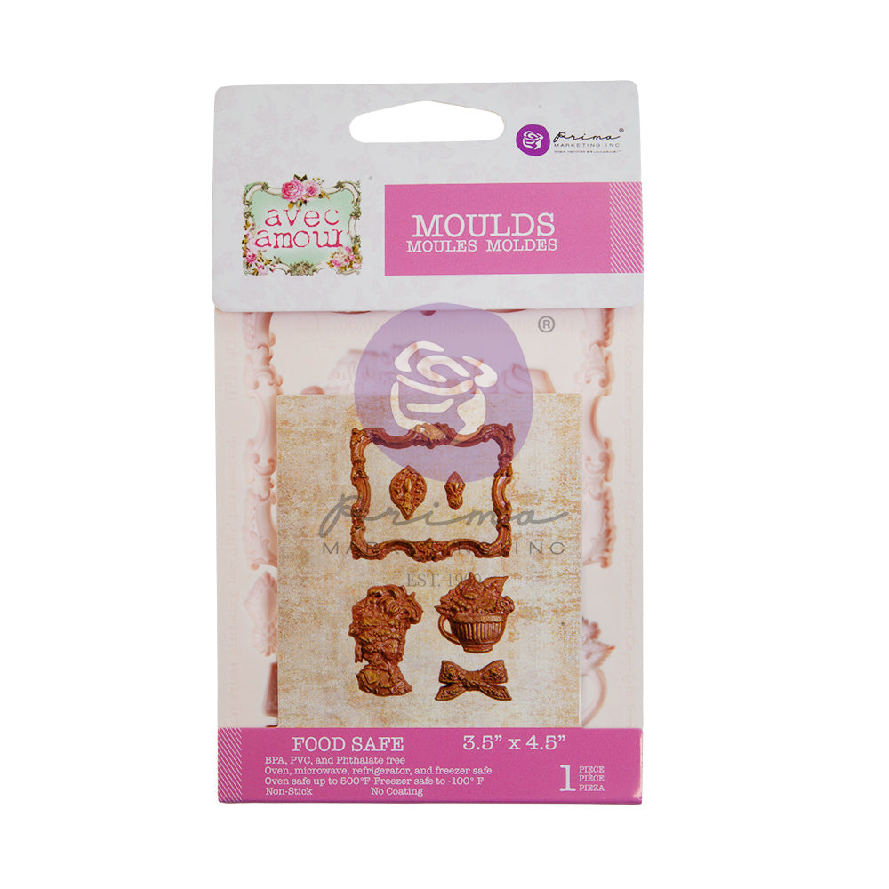 Packaged silicone mould set labeled “Avec Amour Moulds” by Prima Marketing. The packaging features pink and white branding and displays sample cast embellishments including an ornate frame, decorative accents, a floral bust, a fruit basket, and a bow. The mould is food safe and sized 3.5" x 4.5", intended for detailed decorative casting projects.